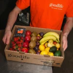 Repartidor de Goodlife sosteniendo una caja de frutas frescas